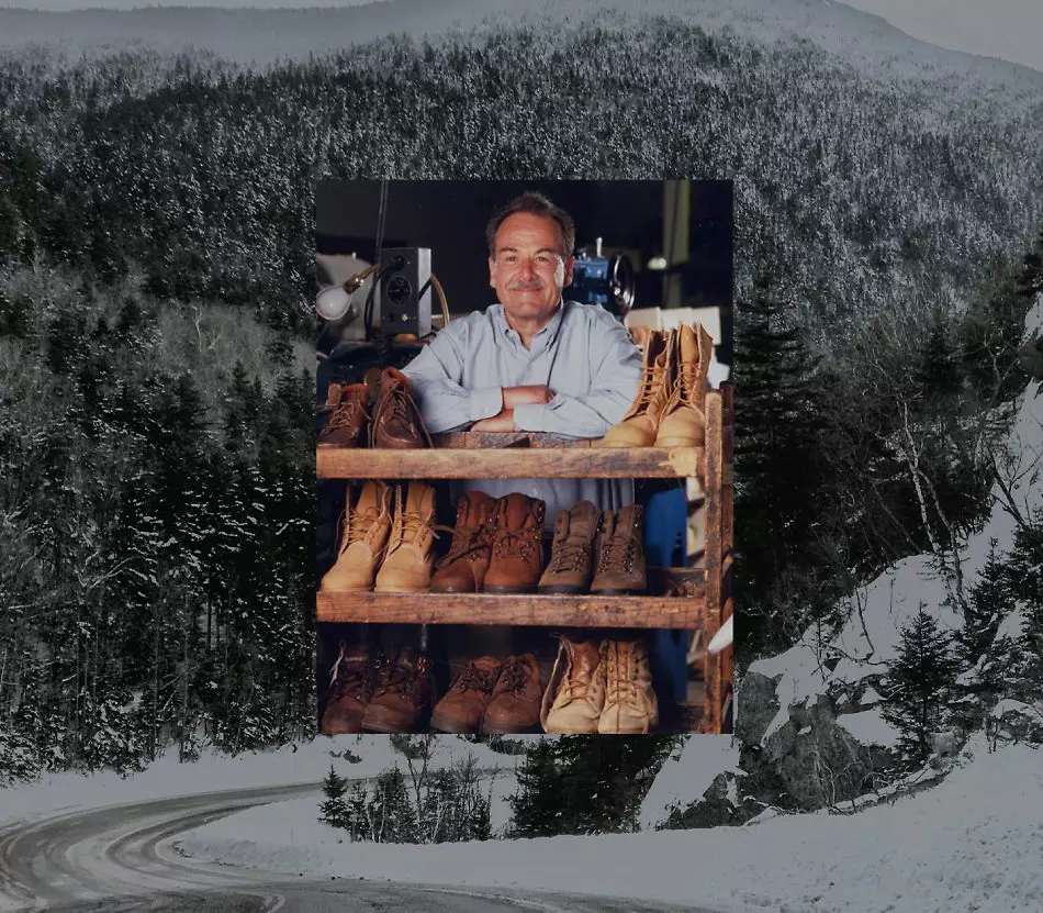 Timberland's Sidney Swartz, a middle-aged man smiling and leaning against a rack of worn-out Timberland boots.